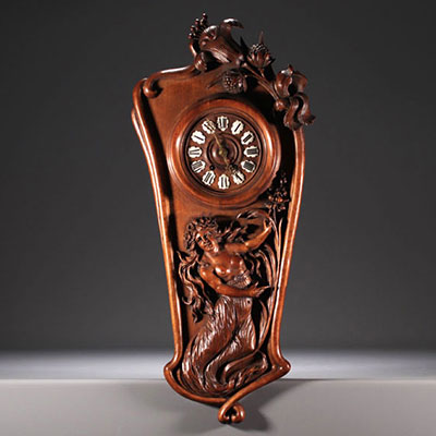 Pendule Art Nouveau en noyer sculpté d'une dame à moitié dévêtue et de décor floral, chiffres en émail, vers 1900.