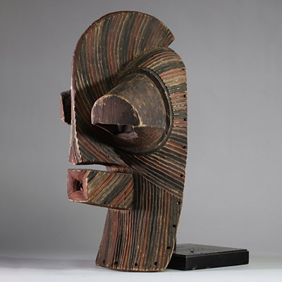 Grand masque Songye Kifwebe « Kilume ». Rd Congo. Bois. De forme allongée, une crête sagittale proéminente, une bouche saillante percée, et surtout des yeux fortement protubérants. Les stries rituelles incisées en spirale alternent des pigments bruns, noirs et ocre clair. Ce type de masque est conçu pour impressionner et symboliser les forces occultes ou sociales. La patine extérieure est mate, pr