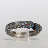 Chine, bracelet rigide en argent et émaux polychromes à décor de dragons affrontés, XIXe siècle Bracelet ouvrant finement ciselé en argent, à décor en fort relief de deux dragons stylisés se faisant f