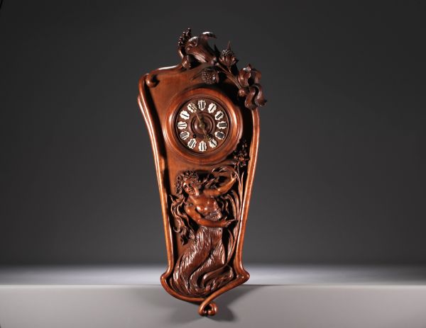 Pendule Art Nouveau en noyer sculpté d'une dame à moitié dévêtue et de décor floral, chiffres en émail, vers 1900.