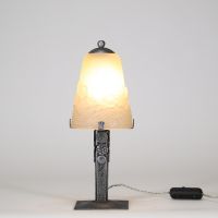 Muller Frères, Lunéville, vers 1930 Ensemble de deux lampes Art Déco en verre moulé-pressé et monture en métal ouvragé à finition nickelée mate.  Chacune des lampes repose sur une base rectangulaire en métal travaillé au repoussé, présentant une surface texturée de motifs géométriques martelés typiques de la période Art Déco. Le fût vertical, orné de pastilles et de stries régulières, soutient une