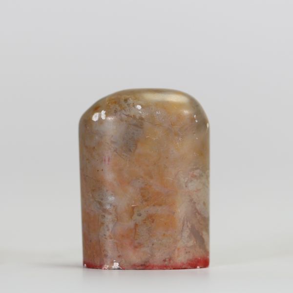 Sceau chinois ancien en pierre dure veinée, gravé à la base de caractères stylisés en rouge  Sceau chinois en pierre naturelle, de forme légèrement bombée, à pâte veinée de tons bruns et orangés. La b