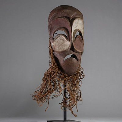 Masque Bembé, RD Congo. Bois, raphia. Présentant des yeux et une bouche en demi-lune, typique de la tradition Bembé (RDC). Polychromie rouge et blanche symbolique, expression dramatique, patine ancienne. Utilisation probable lors de rituels funéraires ou initiatiques. Première moitié du XXe siècle. H : 39 cm.  Collecté sur site par A.S., St Idesbald, début des années 1950