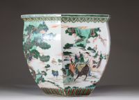 Rare et spectaculaire vase en porcelaine de forme hexagonale, décoré en émaux de la famille verte. Chaque pan du corps présente une scène animée mettant en scène des dignitaires, serviteurs et immortels dans un paysage arboré ponctué de pins, rochers et nuées stylisées. Les personnages, finement détaillés, sont représentés à cheval, à pied ou en conversation, dans un esprit narratif typique de la