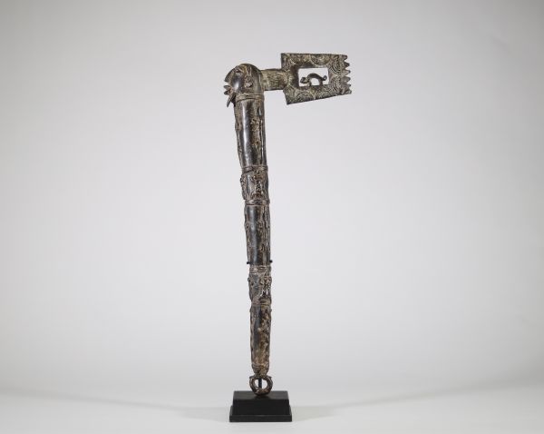 Hache cérémonielle en bronze à riche décor animalier – Afrique, probablement Congo, XXe siècle Hache cérémonielle coulée en bronze à patine foncée, ornée d’un décor finement ciselé figurant une tête anthropomorphe au sommet du manche, et une lame en forme de tranchant rectangulaire ajouré, décoré de motifs concentriques. Le fût présente une remarquable composition en relief représentant une faune