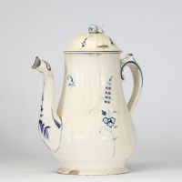Boch Luxembourg, vers 1790–1810 Cafetière en faïence fine ivoire à décor bleu sous couverte Cafetière à panse godronnée et décor peint en bleu de bouquets stylisés, feuillages et frises. Bec zoomorphe à décor stylisé, anse sinueuse soulignée de filets. Couvercle à prise en toupie, chaînette d’origine reliant couvercle et anse. Élégant modèle typique des premières productions de la manufacture de S