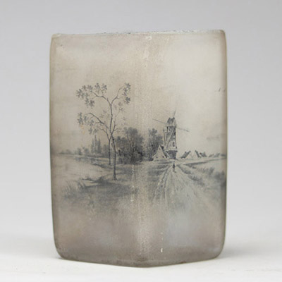 Daum Nancy, vase losangique à décor émaillé en grisaille, scène hollandaise au moulin Raffiné vase en verre opalescent de forme losangique, à décor peint en grisaille représentant une scène hollandaise avec moulin, maisons et silhouettes de voiliers. La finesse du trait et le rendu atmosphérique confèrent à cette pièce un charme poétique propre à certaines productions de la maison Daum. Signature