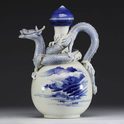 Japan - A white-blue porcelain teapot decorated with a mountain landscape and surmounted by a dragon in relief, Meiji period.