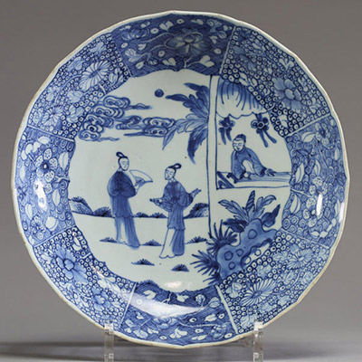 Chine - Assiette festonnée en porcelaine blanc bleu à décor de personnages  Assiette en porcelaine à bord festonné, décorée en bleu sous couverte de personnages dans un jardin et de panneaux floraux s