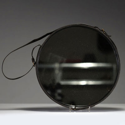 Jacques ADNET (1900-1984) Wall-mounted mirror with circular metal frame entirely sheathed in black leather, fastening strap ending in a brass buckle, circa 1950.