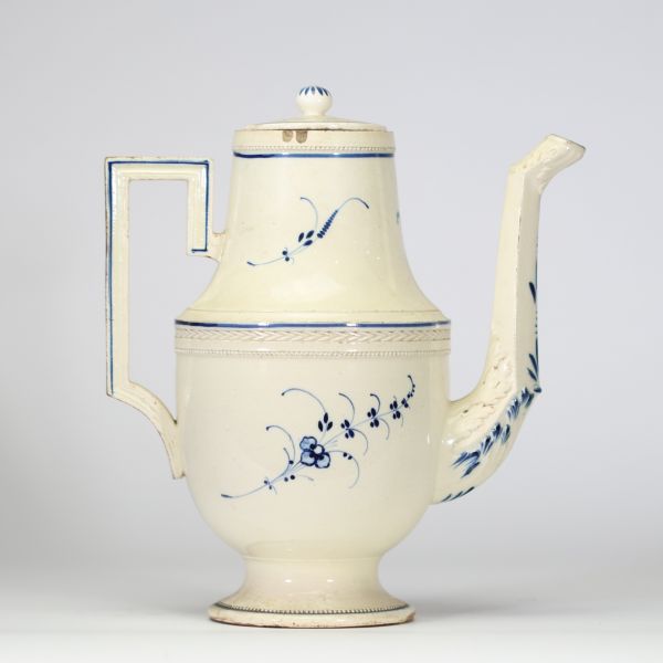 Boch Luxembourg, vers 1790–1810 Cafetière en porcelaine fine à décor bleu sous couverte Modèle de forme Directoire, à panse moulurée, couvercle bombé à prise bouton en toupie, anse à angles vifs et bec en tête zoomorphe stylisée. Décor de rinceaux végétaux, frises dentelées et filets bleu cobalt. Rare exemple du style néo-classique sobre et équilibré développé à la manufacture de Septfontaines.