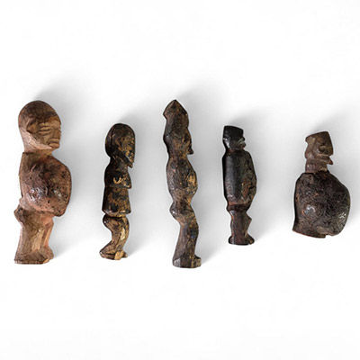 Ensemble de cinq figurines rituelles miniatures Yaka, RD Congo, bois, raphia. H : de 7 à 11 cm. Rare ensemble de petites figurines anthropomorphes utilisées dans le contexte rituel des Yaka (Kwango-Kwilu), au sud-ouest de la RDC. Ces sculptures miniatures, marquées par une forte stylisation et des traces rituelles (pigments, craquelures, dépôt), étaient utilisées comme fétiches de protection ou de