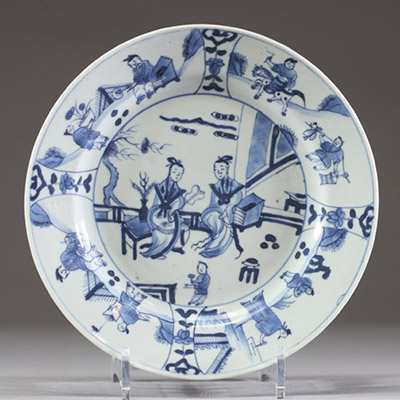 Chine – Assiette en porcelaine à décor bleu sous couverte représentant des scènes animées de personnages dans un jardin. XVIIIe siècle.
