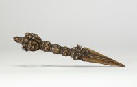 Rare phurba tibétain avec son fourreau, triple lame triangulaire et décoré à la poignée d’une tête de divinité courroucée finement ciselée son fourreau d’origine en cuir gravé, de forme effilée, avec son cordon de suspension, élément rare pour ce type d’objet. probablement XVIIIe siècle