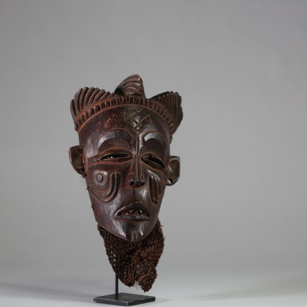 Ancien masque tribal avec coiffe « Mwana pwo » Chokwe/ Tshokwe, RD Congo, Angola. Bois, raphia. Le visage est de forme légèrement allongée, avec un front large et bombé qui s'effile vers un menton délicat. Les proportions sont harmonieuses, créant une impression de calme et de sérénité. Nez fin et droit. Nombreuses scarifications dont « cingelyengelye » sur le front, l’emblème royal. Très belle pa