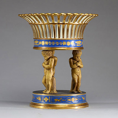 Milieu de table en porcelaine blanche, bleue et or, corbeille ajourée supportée par trois amours, Empire.