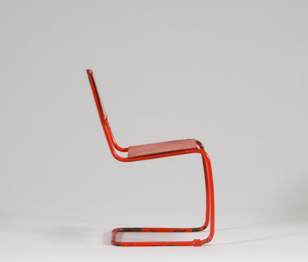 Petit jouet de style Bauhaus Chaise miniature en fer peint rouge-orangé – Vers 1930 Ce petit siège-jouet, en fer peint d’un rouge-orangé vif, évoque clairement l’univers du Bauhaus, tant par ses lignes épurées que par l’usage de matériaux industriels. L’objet n’est pas signé, mais sa forme minimaliste et fonctionnelle, ainsi que son échelle réduite, laissent penser à un jouet éducatif conçu dans l