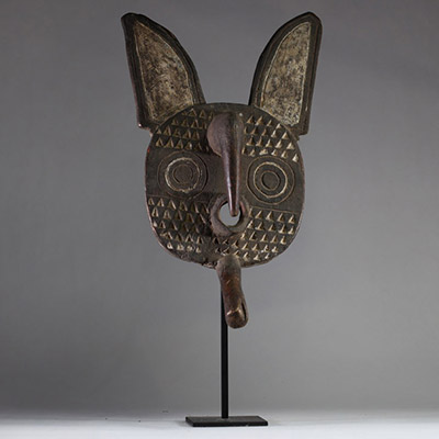 Masque zoomorphe Bobo ( Fing),ouest Burkina Faso. Bois. De forme ovale aplatie, comportant deux grandes oreilles verticales, un nez proéminent sculpté en relief, ainsi qu'une excroissance buccale tubulaire. La surface est décorée de motifs géométriques triangulaires en relief, organisés de manière symétrique autour du visage. Les Bobo utilisent ce type de masque lors de rituels agraires, pour favo