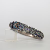 Chine, bracelet rigide en argent et émaux polychromes à décor de dragons affrontés, XIXe siècle Bracelet ouvrant finement ciselé en argent, à décor en fort relief de deux dragons stylisés se faisant f