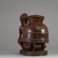 Oracle à souris ( bo num) Baoulé,  côte d’Ivoire. Bois dense, relativement ancien, à patine brune, représentant une figure masculine  assise, soutenant un récipient divinatoire circulaire finement décoré. Un trou circulaire obturé sous la base atteste de l’usage rituel de cette pièce, destinée aux pratiques divinatoires du devin (komien). Le style correspond à la statuaire Baoulé classique du cent