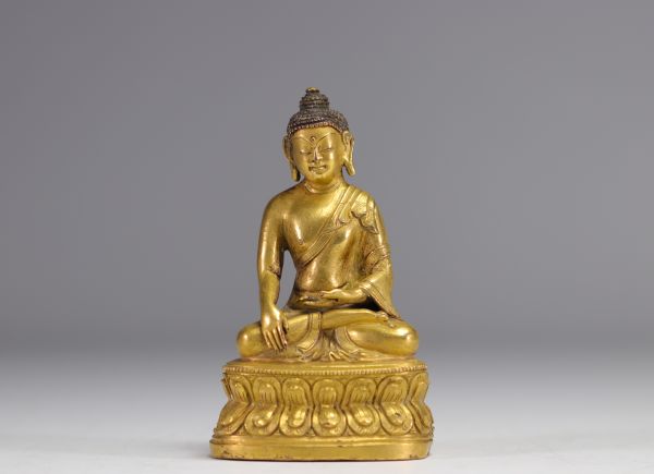 Sculpture d'un bouddha assit sur un socle en bronze doré