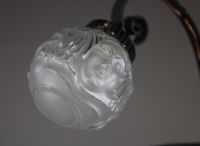 André HUNEBELLE (1896-1985) dans le goût de - Lampe pied fumer en fer forgé martelé et globe en verre moulé pressé à décor de visages de femmes, vers 1920-30.