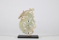Pendentif en jade vert à décor de deux Chilong, Chine, dans le style des Royaumes combattants Pendentif ajouré en jade vert translucide, finement sculpté d’un décor en léger relief figurant deux dragons chilong entrelacés aux corps sinueux, ponctués de motifs spiralés en bosse. Le traitement du relief, la composition symétrique et la stylisation des têtes évoquent les productions du style archaïsa