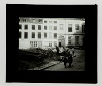 Léon Herlant (1873-1968) — 2 photos positives sur plaques de verre, 8,5 x 10 cm.  Cet ensemble de deux plaques photo positives noir et blanc capture la scène d’un chantier urbain à Bruxelles au 19e siècle, probablement dans la rue du Marais, une rue emblématique de la ville. La scène prend place dans un quartier où l’architecture néo-classique bruxelloise est omniprésente. Les bâtiments à l’esthét