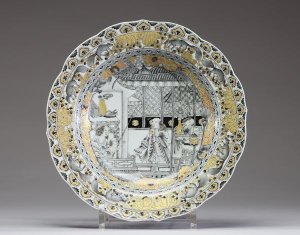 Chine – Assiette en porcelaine de la Compagnie des Indes à décor peint en grisaille et or d’une scène de famille, XVIIIe siècle. Charmante assiette à bord chantourné en porcelaine, décorée en grisaill