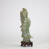 Statuette en jade céladon représentant une élégante, Chine, dynastie Qing, XIXe siècle Sculptée dans une pierre jade céladon nuancée, la figure incarne une jeune femme debout tenant un vase fleuri à l