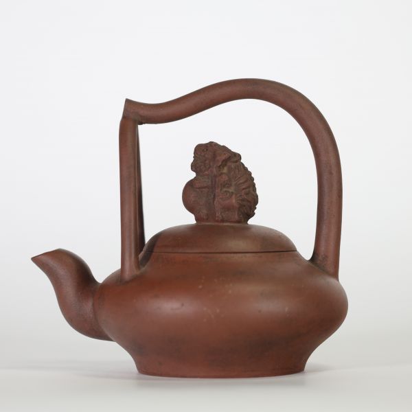 Chine, théière en grès de Yixing à anse surélevée et couvercle orné d’un lion bouddhique, XIXe siècle Théière de forme aplatie en terre cuite brune de Yixing, à anse haute ondulante et bec verseur en 