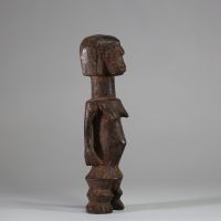 Statuette Zandé « Yanda » ( société mani) , RD Congo. Bois. De forme élancée mais sur des jambes courtes et trapues, les pieds bien définis. Le ventre est légèrement gonflé au niveau de l’ombilic, ce qui est une caractéristique courante de l’art Zandé. Les bras le long du corps. Belle patine usée par l’usage. H : 28,5 cm.  Collecté sur site par A.S., St Idesbald, début des années 1950