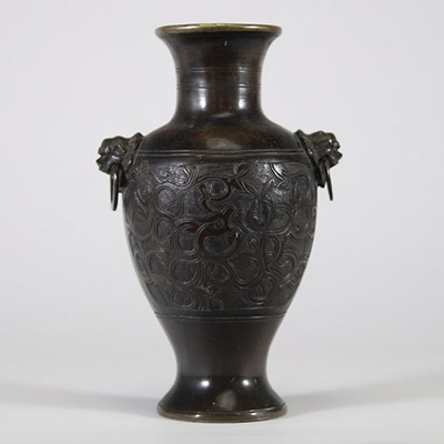 Vase en bronze à décor archaïsant et anses en têtes de lion, Chine Élégant vase en bronze de forme balustre, reposant sur un pied évasé et doté d’un col évasé à bord légèrement ourlé. Le corps est entièrement orné en léger relief d’un décor sinueux de rinceaux et volutes évoquant les motifs archaïques de la période des Royaumes Combattants ou des bronzes rituels Shang-Zho