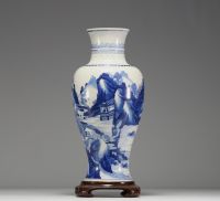 China - White and blue porcelain vase decorated with landscape and characters, wooden base, blue mark under the piece.