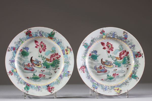 Paire d’assiettes en porcelaine de Chine à décor famille rose de canards mandarin et personnages, dynastie Qing, XVIIIe siècle Paire d’assiettes en porcelaine fine émaillée en polychromie de la famille rose, présentant un décor central délicatement animé de canards mandarin nageant parmi les lotus en fleur, symboles de fidélité conjugale et de pureté. Le pourtour richement orné figure un
