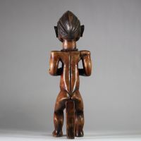 Figure d’ancêtre Fang Mabea ( Byeri), Sud-Cameroun (zones de Kribi, Akom II, Bipindi) . La posture est semi assise, les deux mains jointes tenant une corne de libation, symbole d’offrande aux ancêtres. La coiffure est finement striée, typique du style Fang-Mabea. Un appui dorsal vertical permet de stabiliser la posture. Une scarification frontale est visible entre les sourcils, les prunelles sont