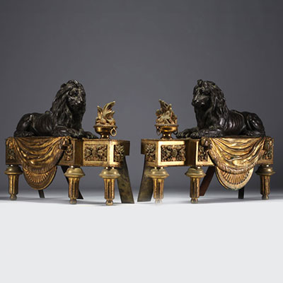 Pair of ormolu and patinated and gilt bronze andirons representing lions lying in front of a flame, 19th century.