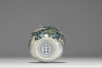 Chine - Vase en porcelaine polychrome à décor de paysage, socle en bois, marque au bleu sous la pièce.