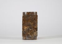 Tube cong en jade brun, Chine, dans le goût de la période Shang ou Zhou Forme tubulaire à section carrée perforée d’un cylindre central, réalisée dans un jade brun veiné de noir et d’ocre, à surface polie mais irrégulière. Ce type d’objet, appelé 