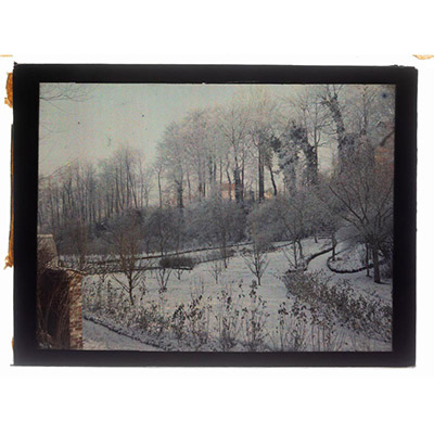 Léon Herlant (1873-1968) — autochrome sur plaque Lumière», 12 x 9 cm.  Paysage de Watermael-Boitsfort sous la neige, Sous la lumière douce et dorée d’un matin d’hiver, ce paysage enneigé déploie une atmosphère magique et silencieuse, empreinte de mystère. La scène évoque irrésistiblement l’univers de Pieter Bruegel l’Ancien, par son traitement poétique de la nature figée et son rendu sensible des