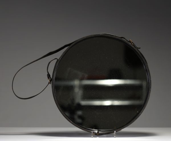 Jacques ADNET (1900-1984) Wall-mounted mirror with circular metal frame entirely sheathed in black leather, fastening strap ending in a brass buckle, circa 1950.