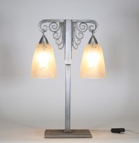 J. Vandôme & Muller Frères Lunéville, vers 1930 Lampe Art Déco à deux lumières en métal martelé nickelé et verrerie signée.  Structure en potence à deux bras terminés par d’élégantes volutes martelées, surmontant un fût vertical en métal à décor rayonnant. La base rectangulaire est signée J. Vandôme, artisan ou maison d’édition réputée pour ses œuvres de ferronnerie décorative dans les années 1930