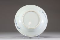 Chine – Assiette en porcelaine à décor bleu sous couverte représentant des scènes animées de personnages dans un jardin. XVIIIe siècle.