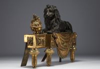 Paire de chenets en bronze patiné et doré représentant des lions couchés devant une flamme, XIXème.