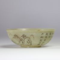 Bol en jade céladon finement gravé d’un paysage montagneux et d’un poème calligraphié, marqué Qianlong  Bol circulaire en jade de teinte céladon très pâle, finement incisé d’un décor continu représent