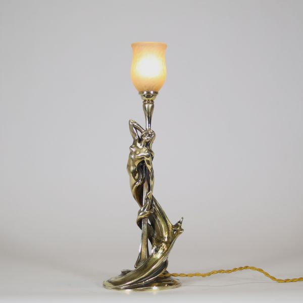 Raoul François Louche (actif au début du XXe siècle) Lampe Art Nouveau en bronze doré et patiné, verrerie signée Schneider  Rare et délicate lampe de table en bronze à patine nuancée représentant une femme nue, élancée et drapée dans un mouvement tourbillonnant, typique du style naturaliste et sensuel de l’Art Nouveau. Le personnage féminin s’élève avec grâce pour former le corps du luminaire, ses