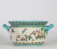 Théodore Deck (1823–1891) Importante jardinière en faïence émaillée, à décor polychrome d’inspiration extrême-orientale représentant un coq, des oiseaux, des papillons et des branchages fleuris en léger relief, sur fond crème. Frise supérieure ornée de motifs géométriques bleus et or. Ansés latérales en forme de dragons stylisés émaillés turquoise.
