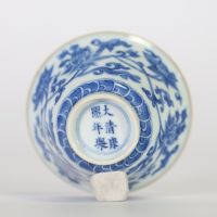 Chine, bol en porcelaine blanc-bleu à décor de fleurs de lotus épanouies et en bouton surmontant une frise de vagues, l'intérieur orné d'une fleur stylisée et la base portant une marque apocryphe à si