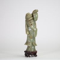 Statuette en jade céladon représentant une élégante, Chine, dynastie Qing, XIXe siècle Sculptée dans une pierre jade céladon nuancée, la figure incarne une jeune femme debout tenant un vase fleuri à l