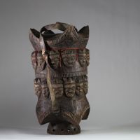 Très rare boîte rituelle de grande taille Pendé, RD Congo. Dotée d’un couvercle emboîtant d’une sangle en cuir permettant le transport. Elle est ornée de 24 visages humains stylisés en frise continue sur le pourtour bois. Des perles rouges sont fixées sur accentuant la dimension rituelle. Une fente ancienne est visible sur un bord, témoignant d’un usage prolongé et d’un vieillissement naturel du b